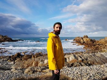 Portrait of man standing on beach against sky