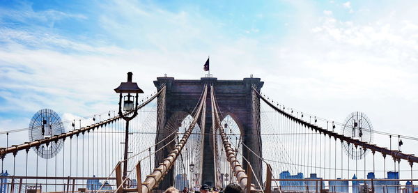 Low angle view of suspension bridge against cloudy sky