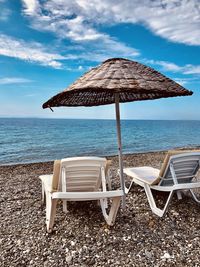 Deck chairs on beach against sky