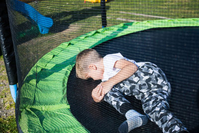 Injured boy lying on trampoline at jungle gym 