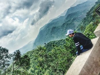 Man standing on rock against sky