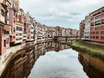 Reflection of buildings in canal against sky