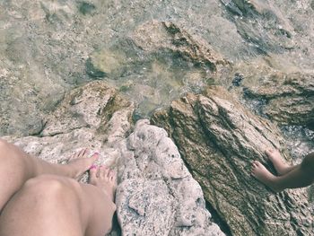 Low section of woman legs on rock at beach