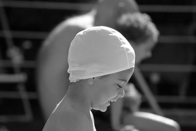 Close-up of smiling shirtless boy wearing swimming cap