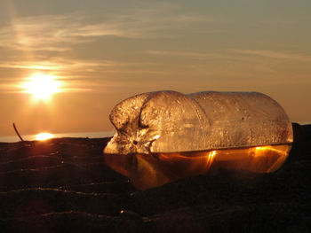 Close-up of ice cream cone on land against sky during sunset