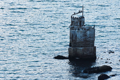 Wooden posts on rock in sea