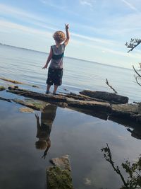 Full length of boy jumping on beach against sky