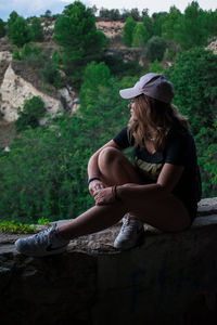 Side view of woman sitting on rock