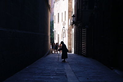 Woman standing in alley amidst buildings