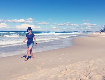 Full length of man walking on beach against sky