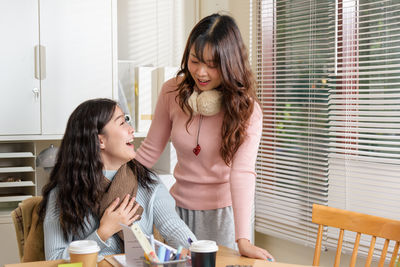 Side view of young woman using mobile phone while sitting at home