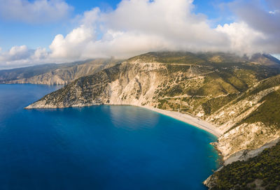Aerial view of sea by mountains against sky