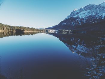 Scenic view of lake and mountains against clear blue sky