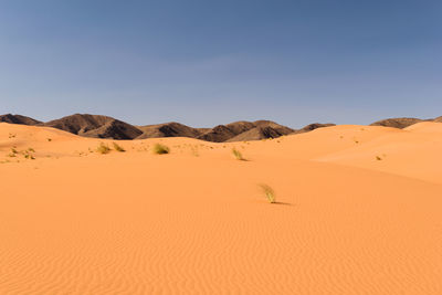 Scenic view of desert against clear blue sky