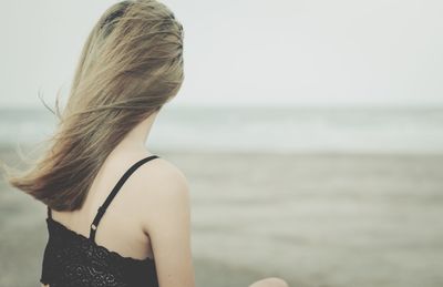 Rear view of young woman standing at beach