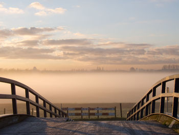 Bridge over sea against sky during sunset