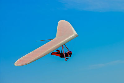 Low angle view of airplane flying against clear blue sky