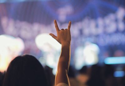 Cropped hand showing horn sign against blurred background