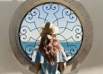 Rear view of young woman looking through window