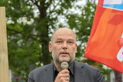 Portrait of man holding umbrella against trees