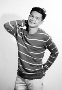 Portrait of young man standing against white background