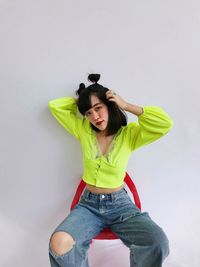 Portrait of woman sitting against white background