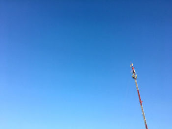 Low angle view of communications tower against clear blue sky