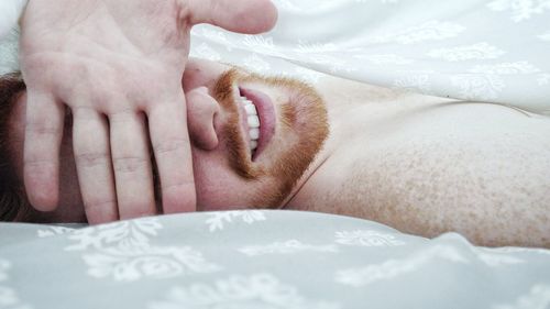 Close-up of smiling young man relaxing on bed at home