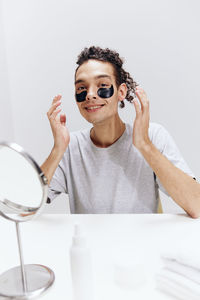 Portrait of young woman wearing sunglasses against white background