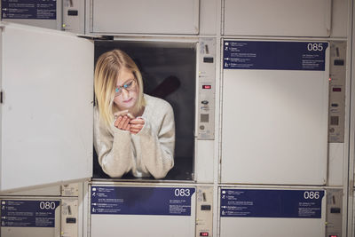 Young woman using phone in locker