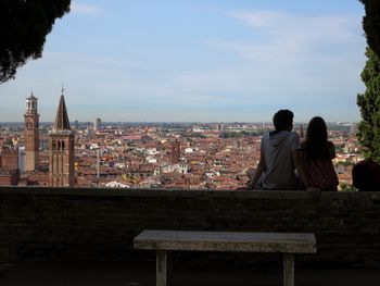 Rear view of couple sitting on wall in old town