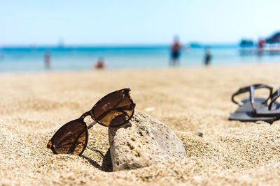 Close-up of butterfly on sand at beach against sky