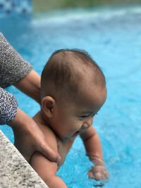 Cropped hands of mother holding baby girl in swimming pool