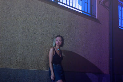 Portrait of a young woman standing against wall