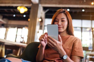 Closeup image of a beautiful young asian woman holding and using mobile phone