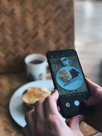 Midsection of person photographing breakfast with mobile phone