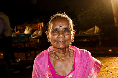 Portrait of woman with pink arms raised at night