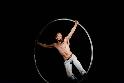 Midsection of man with arms raised against black background