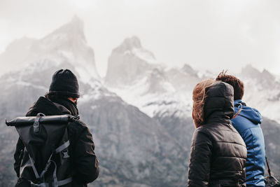 Friends standing against snowcapped mountains