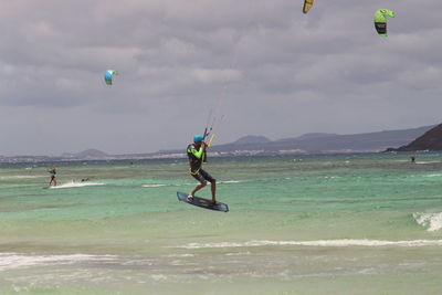 Man paragliding over sea against sky