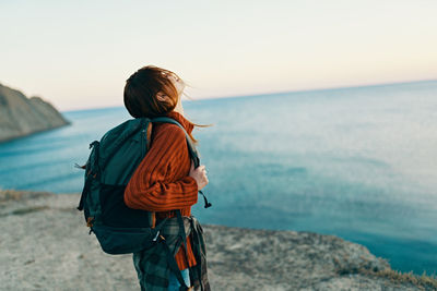 Rear view of man looking at sea shore against sky