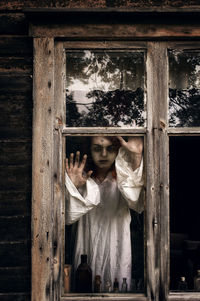 Portrait of depressed woman seen through window