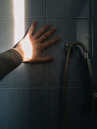 Cropped hand touching wall in bathroom