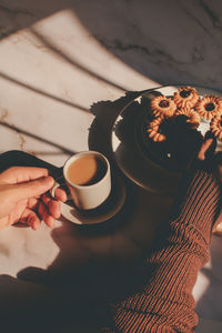 Cropped hand of woman holding coffee on table