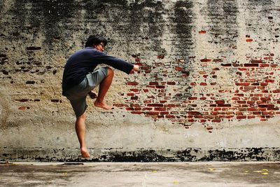 Man jumping against old brick wall