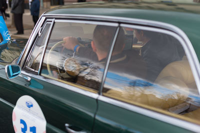 Reflection of woman on side-view mirror of car