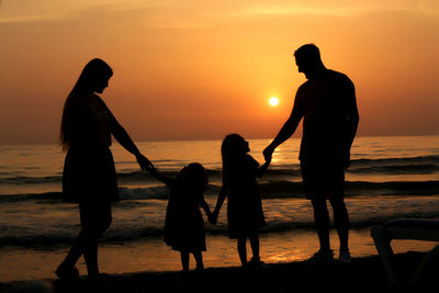 Silhouette family at beach during sunset