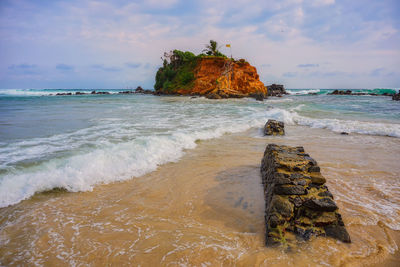 Rock formation on beach against sky