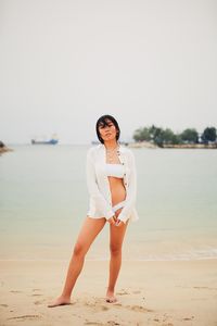 Beautiful woman standing against beach