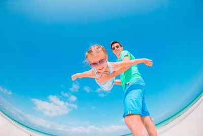 Low angle view of father holding daughter against sky